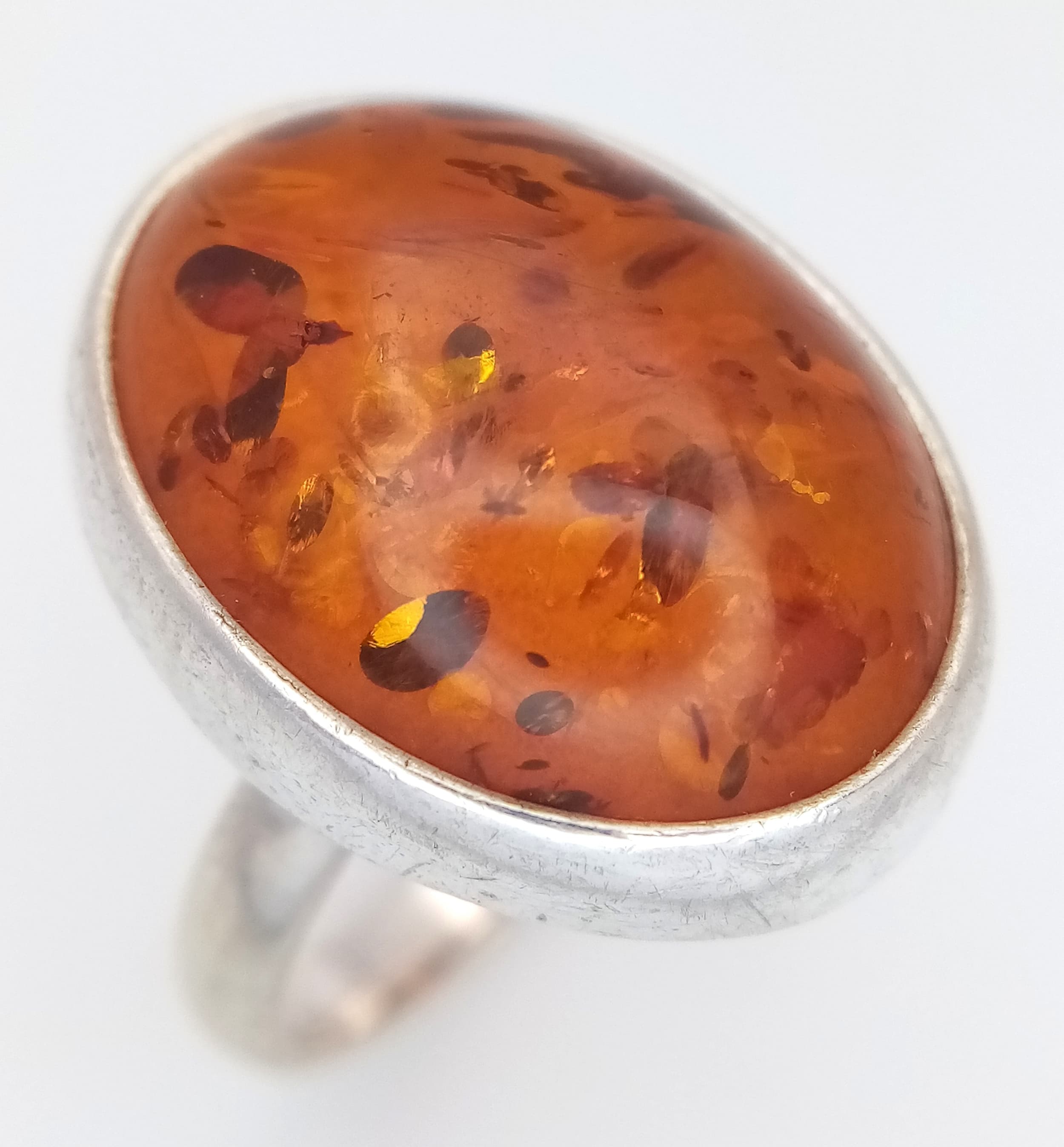 A Vintage Sterling Silver Baltic Amber Cabochon Ring Size P1/2. Set with a 2.1 x 1.6 Oval Baltic Amber in a Modernist Design Mount. Gross weight 7.92grams.
