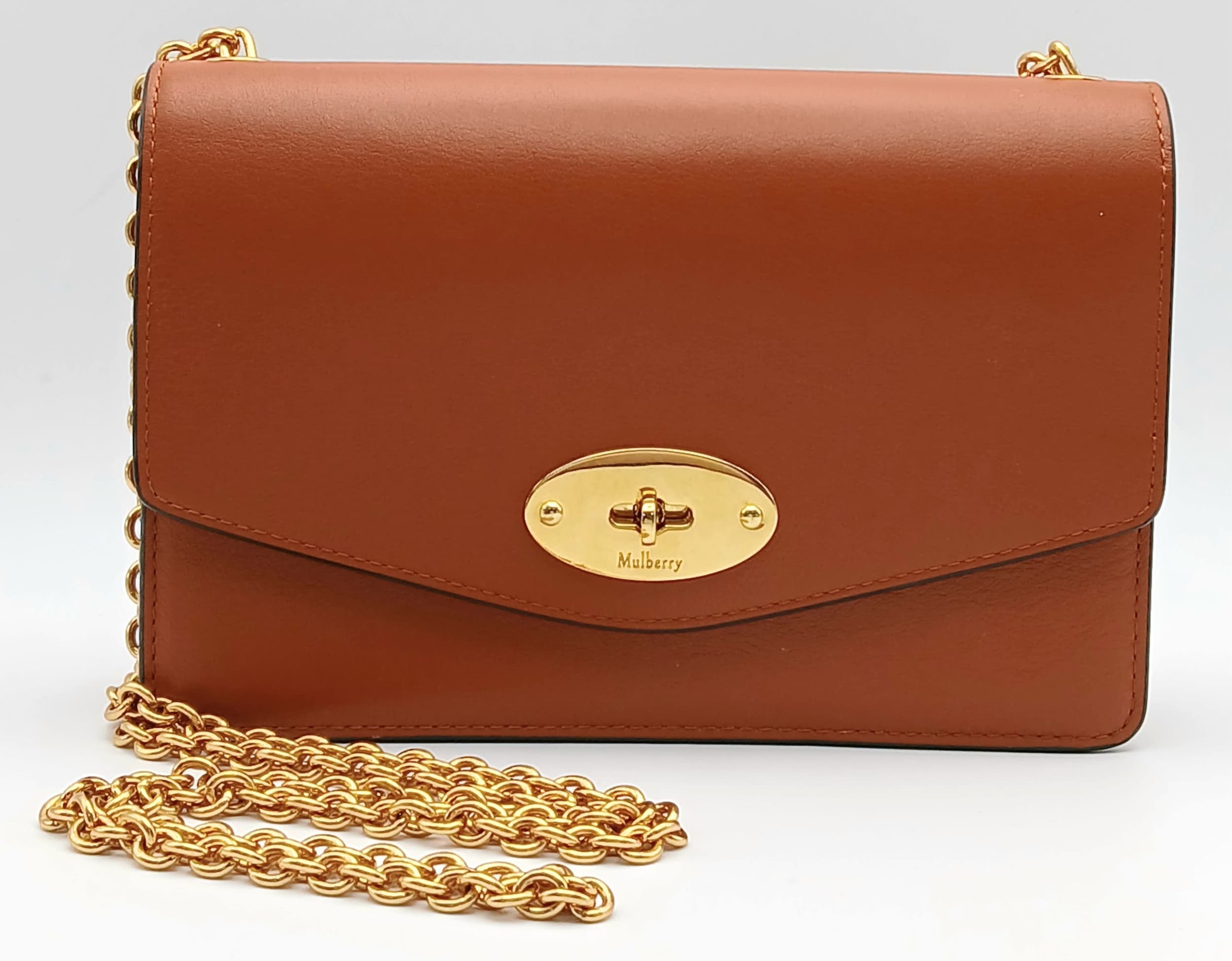 A Mulberry Brown Leather Darley Shoulder Bag. Brown leather exterior with gold-toned hardware, chain shoulder strap and twist lock closure. Black leather interior with one main compartment, a zipped pocket and card slots. Approx 19cm length x 13cm height x 4cm depth. Some scratches and stains to the leather. Comes with a dust cover. Please see photos or request a condition report. Ref: 28641.