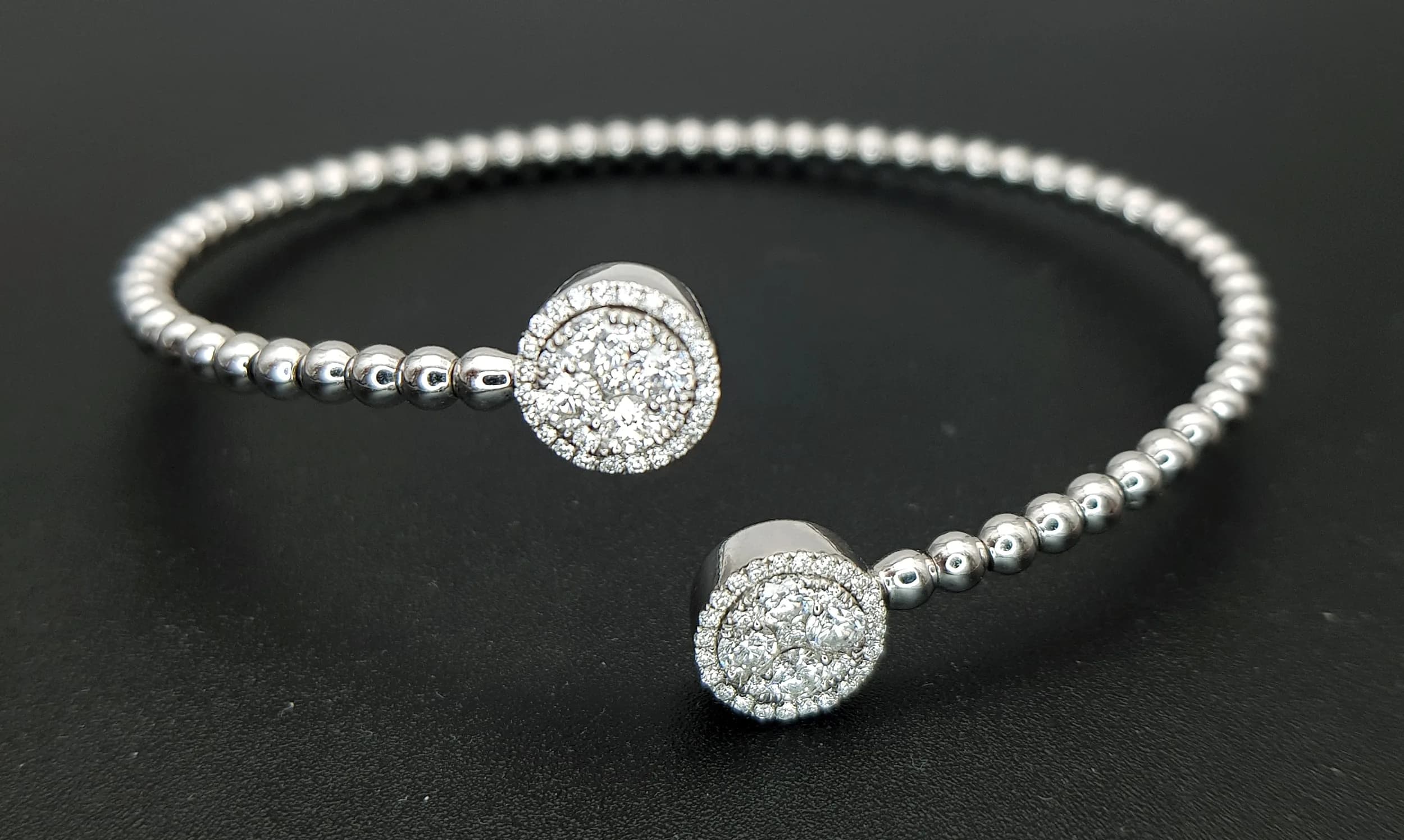 An 18K White Gold and Diamond Cuff Crossover Torque Bangle. Beaded links with diamond cluster tips of c.1ctw of round brilliant cut diamonds. G-H colour with VS2 clarity. 8.54g. MT22.