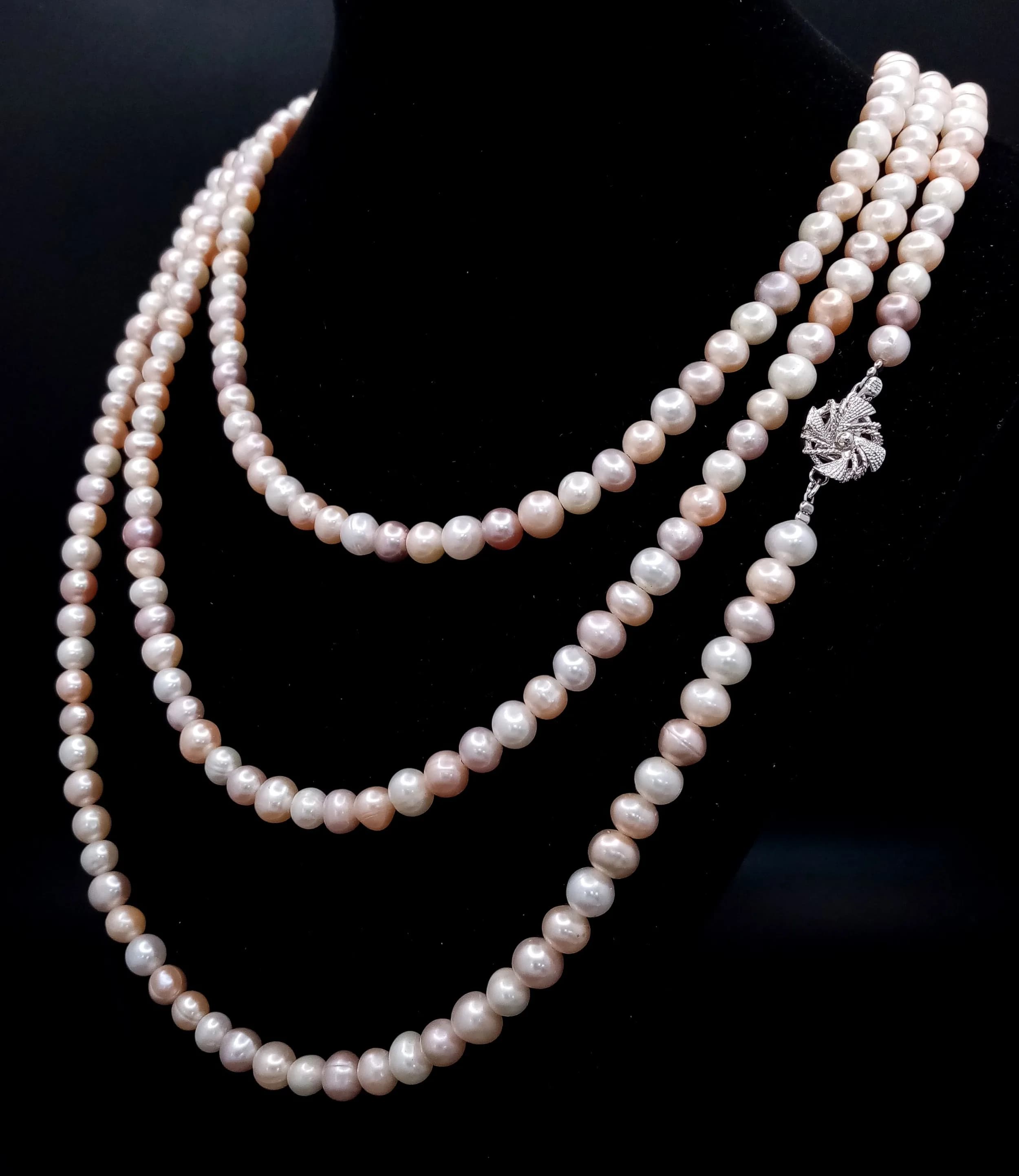 A magnificent rope length Freshwater Pearl Necklace. Varied shades of pastel cream freshwater pearls and fitted with a silver decorative clasp. Total approx 164cm in length. Please see photos for details.