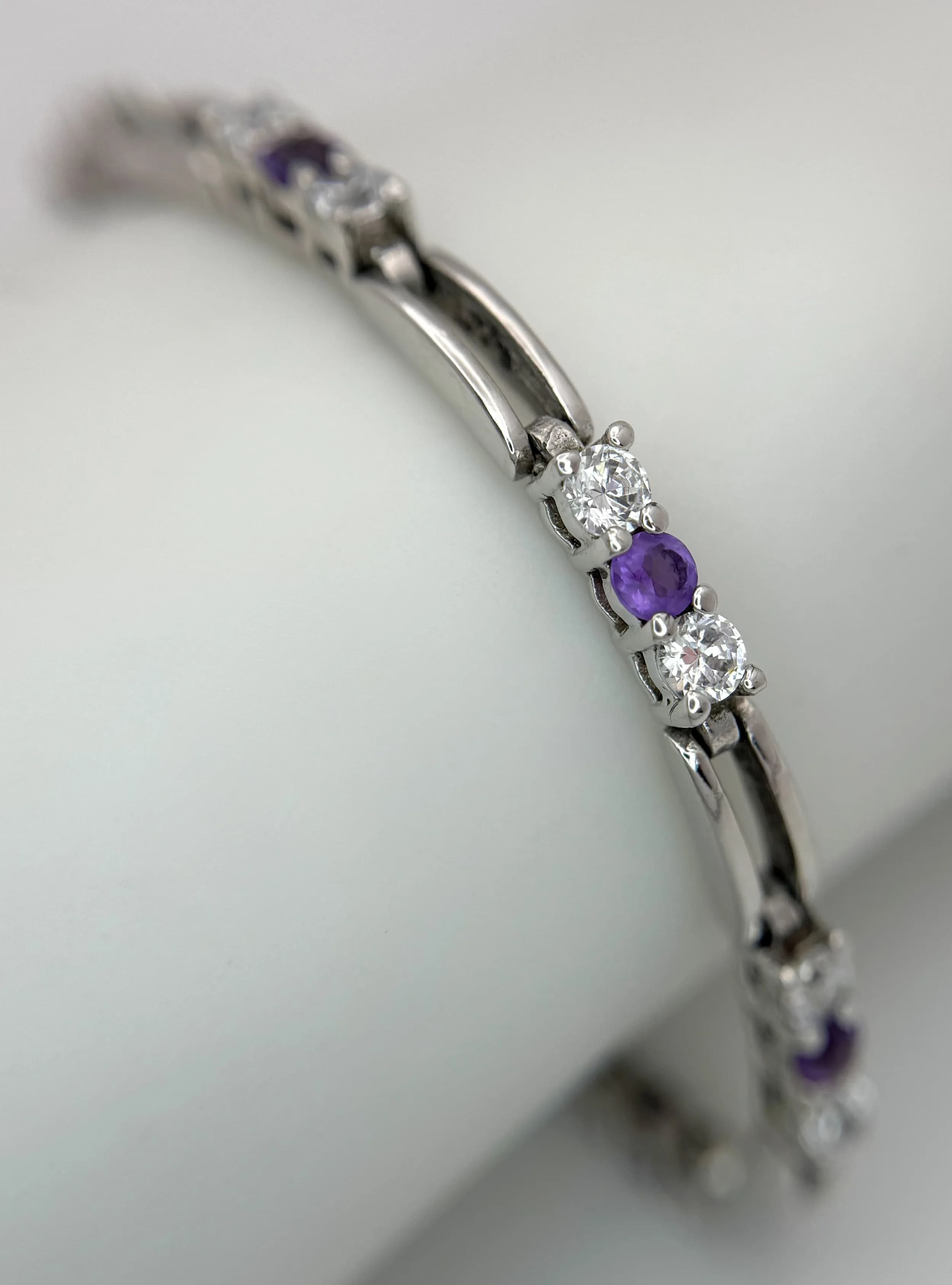 A Pretty Sterling Silver Amethyst and Cubic Zirconia Tennis Bracelet. One fastener side not secure. 19cm Length. 3.5mm Wide. Gross weight 11.16 grams.
