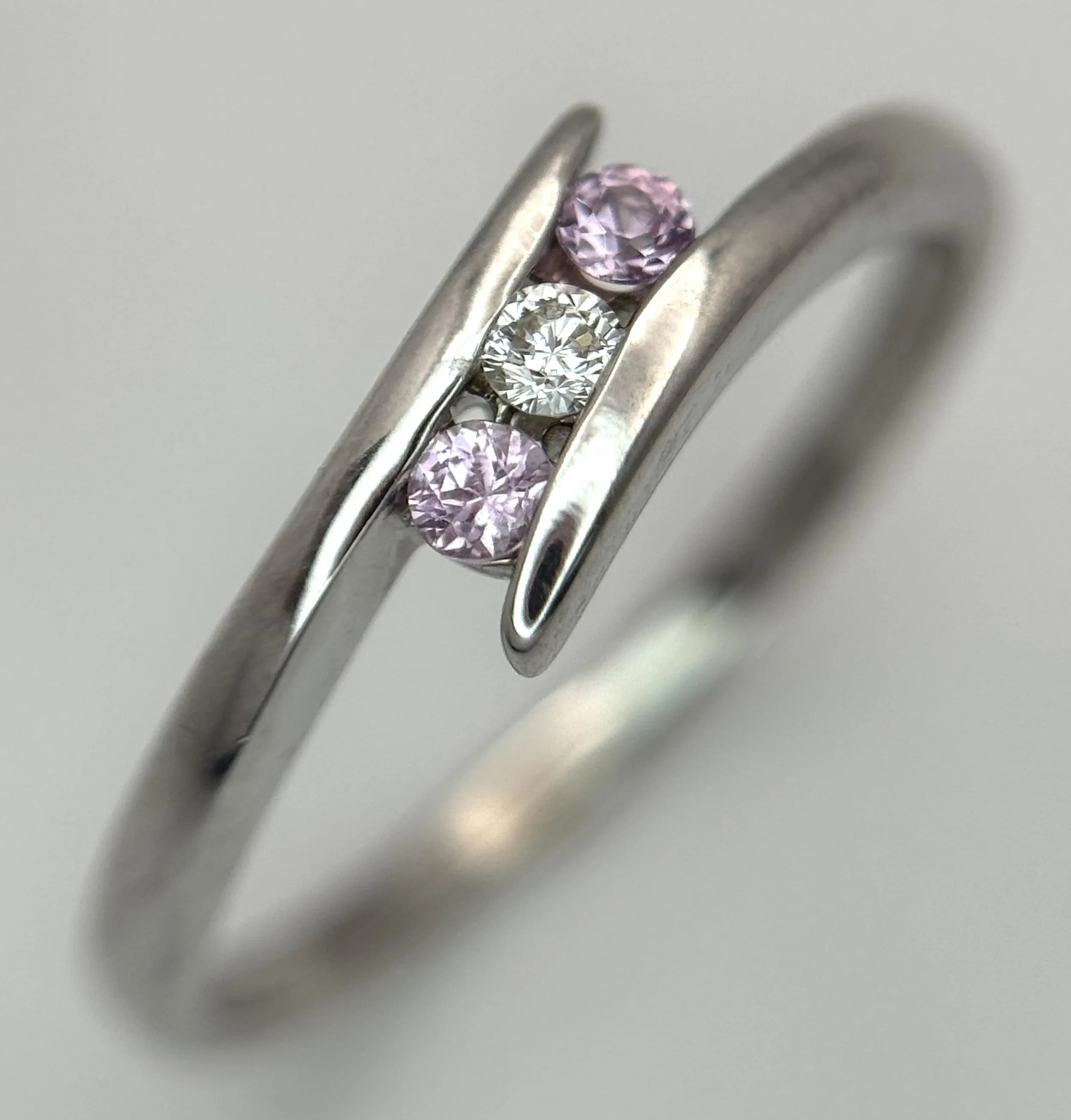 A 9K WHITE GOLD, DIAMOND AND PINK SAPPHIRE SET, CROSSOVER RING. 1.5G, SIZE M 1/2. SC 5006