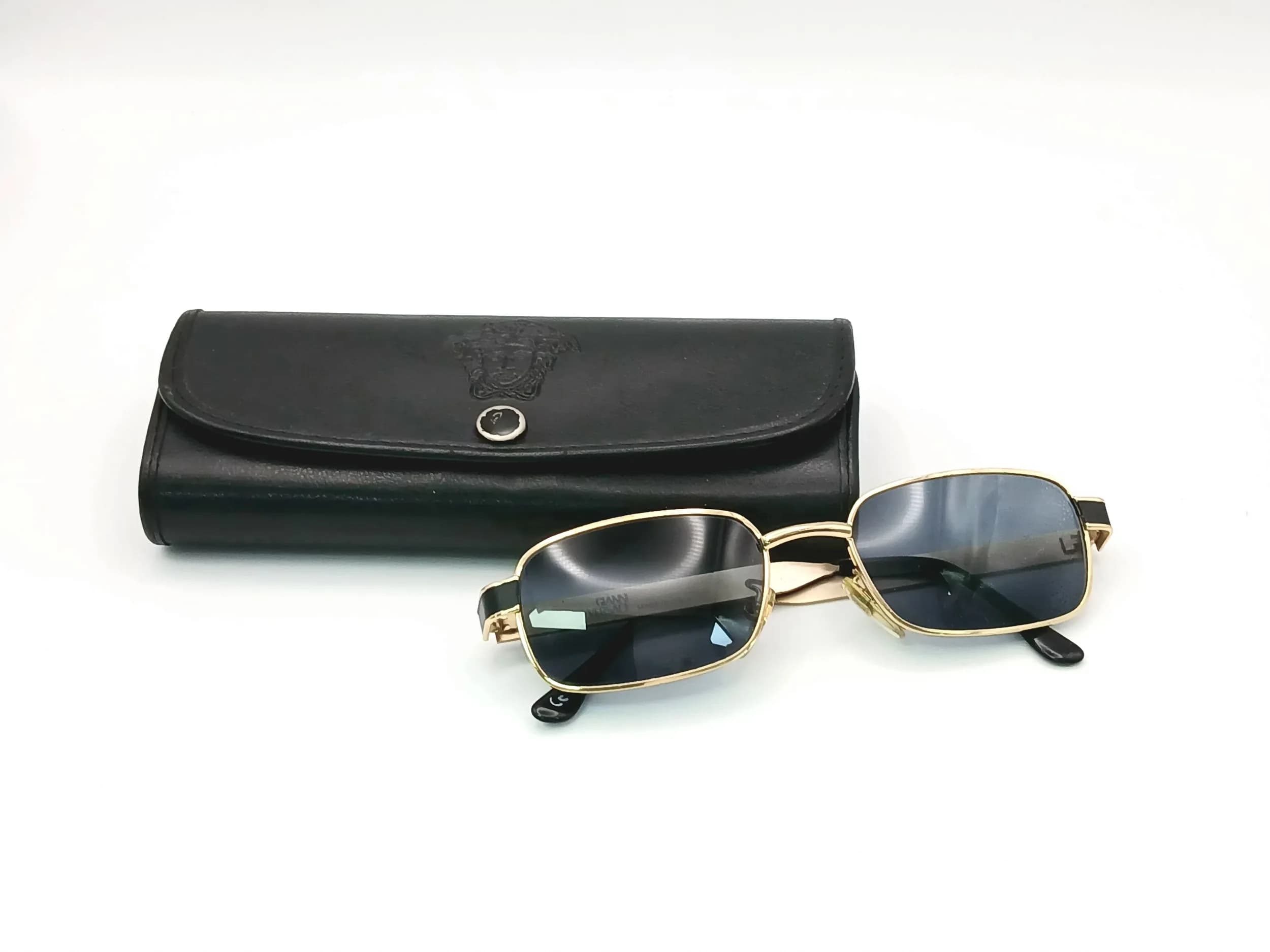 A Pair of Stylish Versace Sunglasses. Geometric decorative gilded pattern. Comes with a Versace case.