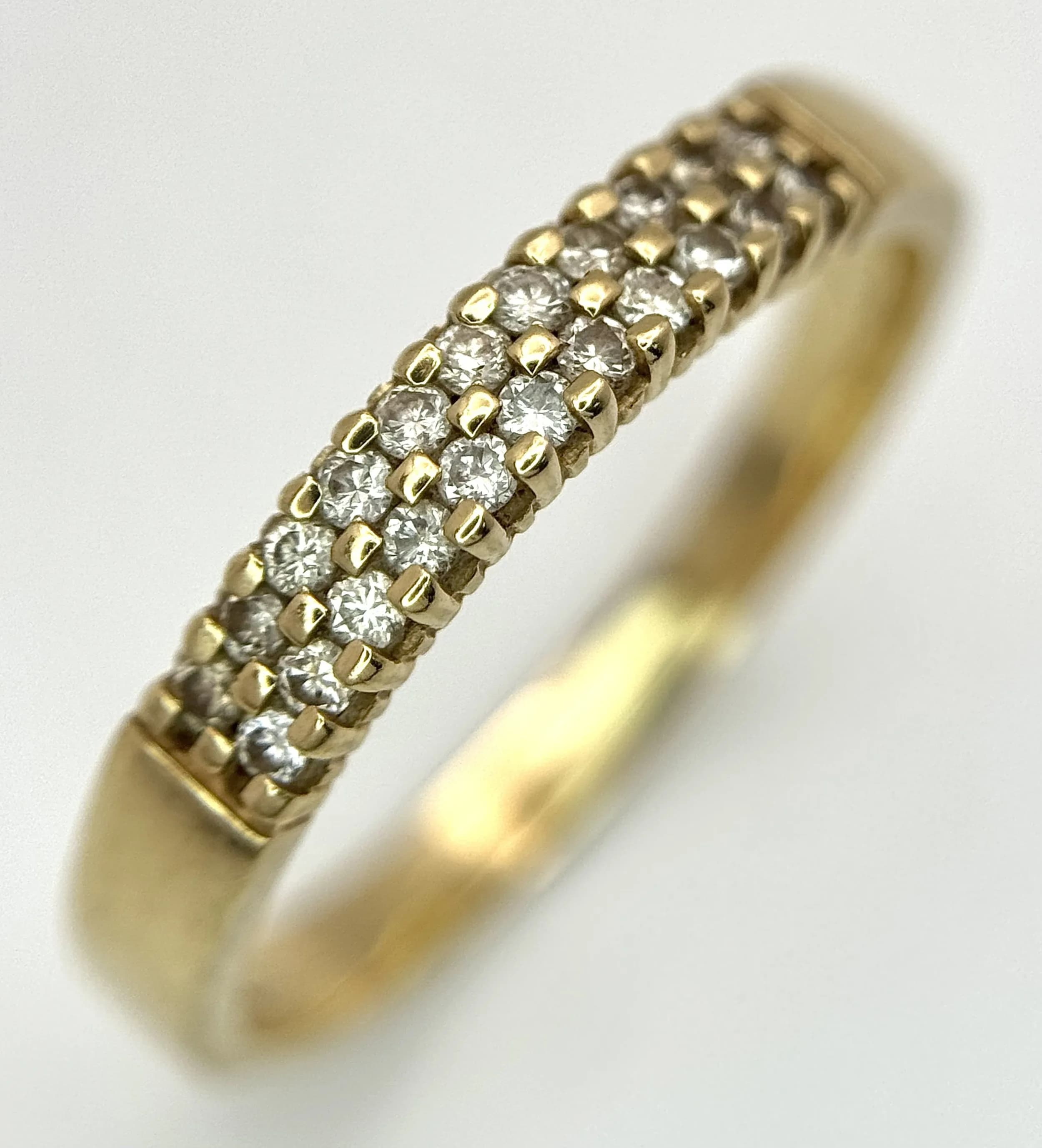 A 9K Yellow Gold and Diamond Band Ring. 0.20ctw of diamonds in a two row, micro-claw setting. Size O 1/2. 1.92g total weight.