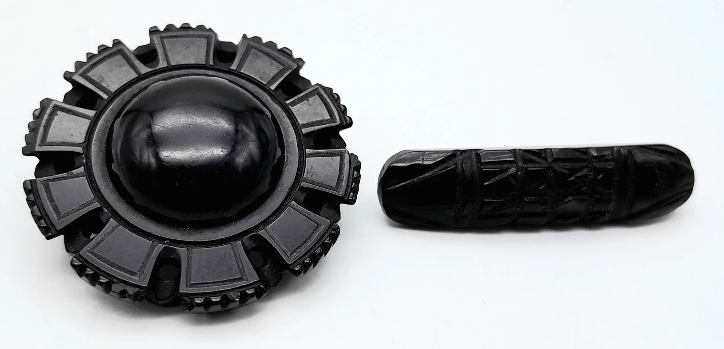 A Victorian Whitby Jet Bar Brooch with hand carved geometric design, plus a further Vintage Round Jet Brooch.