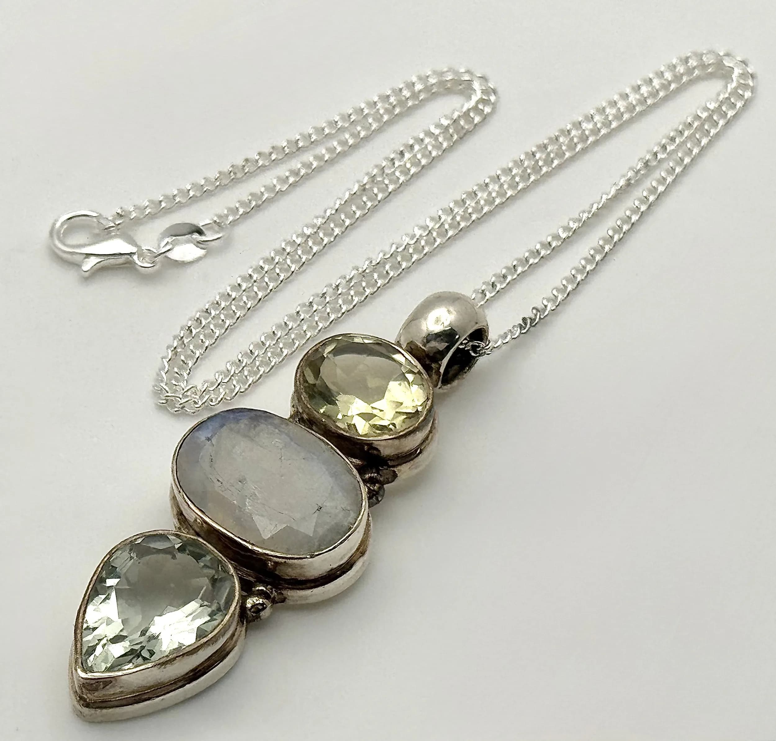A Sterling Silver Citrine and Moonstone Statement Necklace. 46cm Length Chain. The Pendant measures 5.5cm Length and is set with oval and pear cut Citrine with a centre oval cut Moonstone. The Pendant measures 1.9cm wide at its widest point and the Necklace has a gross weight of 18.41 grams